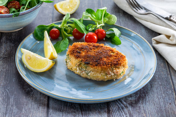 Homemade salmon fish cake with fresh leaf salad garnished with lemon