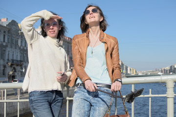 young ladies tourists in Saint Petersburg Russia take selfies on a wooden bridge in the historical city center