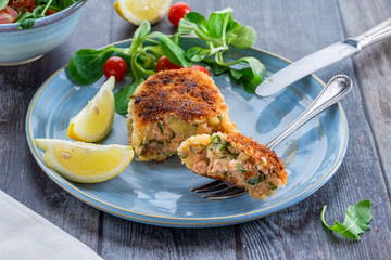 Homemade salmon fish cake with fresh leaf salad garnished with lemon