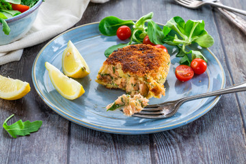 Homemade salmon fish cake with fresh leaf salad garnished with lemon