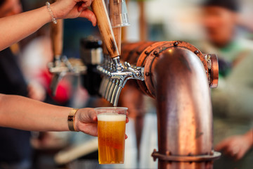 Beer tapping with traditional taps into a plastic cup and colorful  blurred background