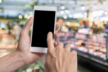Close up of hand holding smartphone with blank black screen(with clipping path for adjust you text) on supermarket in department store background.