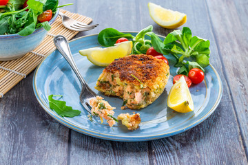 Homemade salmon fish cake with fresh leaf salad garnished with lemon
