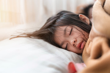 Young asian girl sleeping on white pillow on bed in bedroom in morning time, Selective focus, Copy space.
