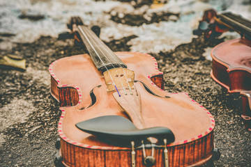 Two violins lie on the asphalt next to the snow