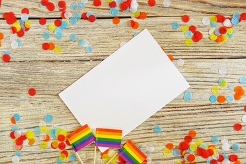 Bright rainbow gay flag on wooden background, paper confetti top view with space for text, mocup, copy space. LGBT community. acceptance symbol