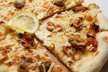 Italian pizza with seafood, mussels and squid, a slice of lemon