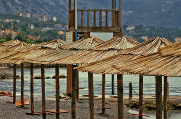 Fototapeta na wymiar horizontal photo with a row of the straw sun umbrellas on empty beach