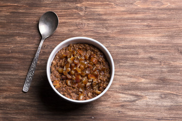 Delicious oatmeal in a white bowl, dates fruits and cocoa. healthy breakfast on a wooden background