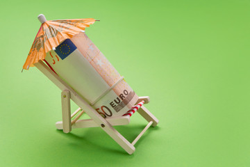 finance concept, a roll of euro notes lying in a deck chair, under an umbrella, as if resting
