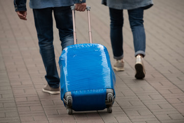 A man carries a suitcase wrapped in blue film