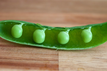 close up of open pea pod on cutting board