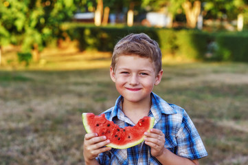 Portrait of a happy boy with a watermelon on a summer day on the street