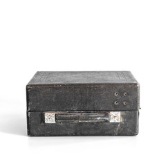 Old black shabby closed suitcase on blue background.  Minimal concept.