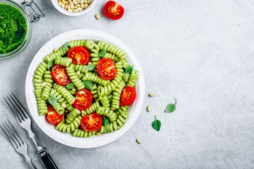 Fusilli pasta with basil pesto sauce , tomatoes and pine nuts.