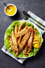 Fried small capelins on a white plate
