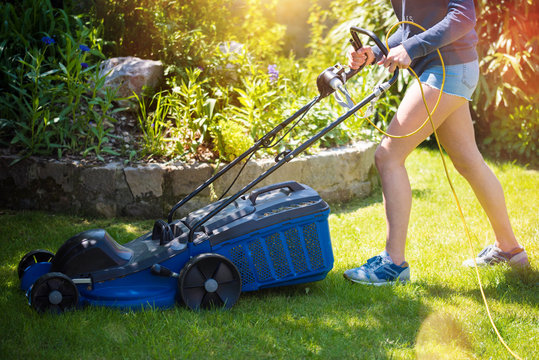 belle jeune femme passant la tondeuse dans le jardin