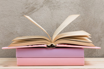 Education and reading concept - group of colorful books on the wooden table, concrete wall blackboard