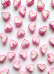 Vertical Image of Pastel Pink and White Heart Shaped Marshmallow Candies Scattered on White Background