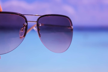 Sunglasses on Blue Sea blurred Background.
