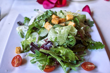 A plate of salad with fresh vegetables and fried bread cubes.