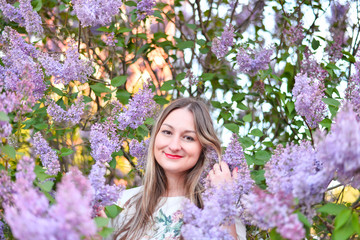Woman with long blond hair in the garden with flowers. Beautiful girl on a sunny day.