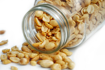 Roasted peanuts in the glass bottle on white background for advertising. Clean food good taste ideas concept. Selective focus and free space for text.