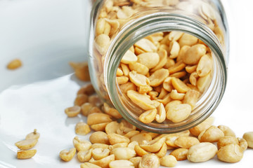 Roasted peanuts in the glass bottle on grey background for advertising. Clean food good taste ideas concept. Selective focus and free space for text.