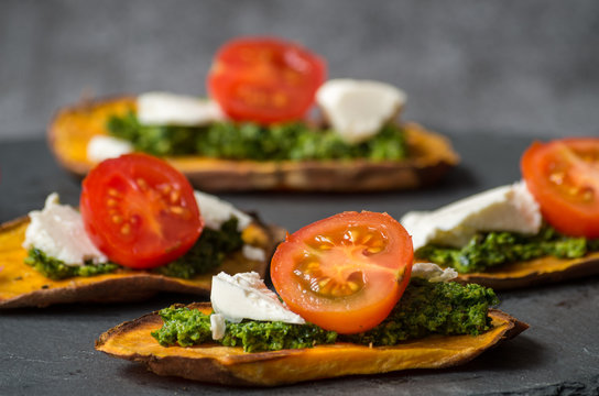 Pieczone bataty z pesto, fetą i pomidorkami koktajlowymi.