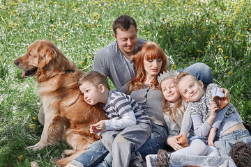 happy family with three kids sitting on the grass in a Sunny Park