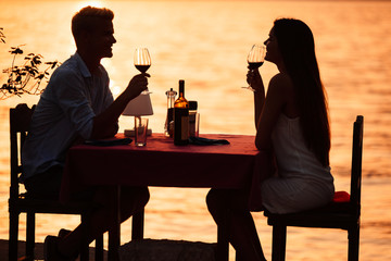 People, vacation, love and romance concept. Young couple enjoying a romantic dinner on beach.