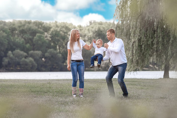 Fototapeta premium happy parents with their little son walking together in spring Park