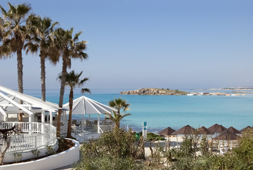 Obraz premium Palms, bar, umbrellas on the beautiful beach in Cyprus.