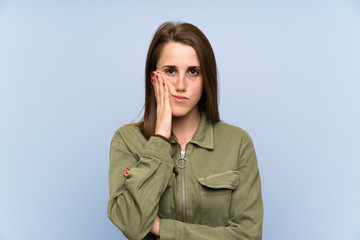 Young woman over isolated blue wall unhappy and frustrated