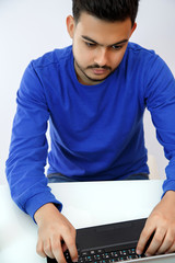 a young guy sitting at a laptop in search of work,doing business on the Internet. on light background