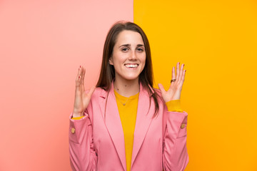 Young woman with pink suit over colorful background laughing