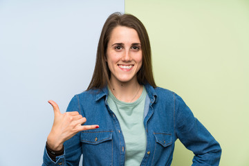 Young woman over colorful background making phone gesture