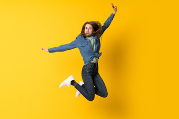 Obraz premium Young woman jumping over yellow background