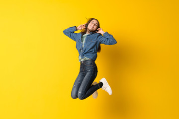 Obraz na płótnie Canvas Young woman jumping over yellow background