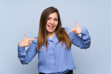 Young girl over isolated blue wall proud and self-satisfied