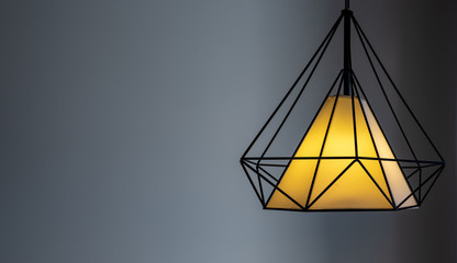 Modern lamp hanging down from ceiling in the dark background.