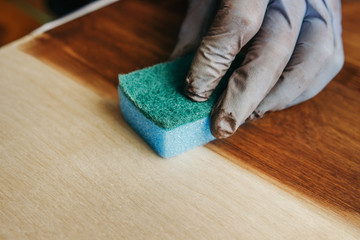 Plywood protection stain. Wood impregnation. Handwork. sponge treatment. Man painting wooden floor....