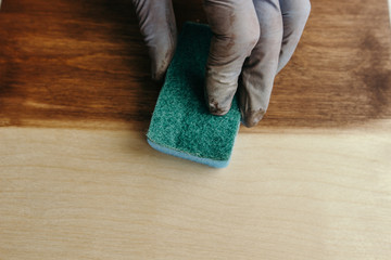 Plywood protection stain. Wood impregnation. Handwork. sponge treatment. Man painting wooden floor. Manual wood coating stain