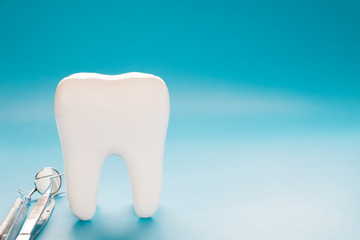 Big tooth and dentist tool on blue background.