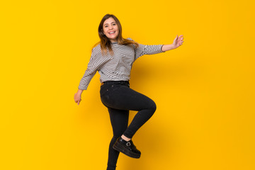 Fototapeta na wymiar Young girl jumping over isolated yellow background
