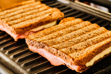 Preparing toast  with ham and cheese on grill