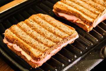 Preparing toast  with ham and cheese on grill