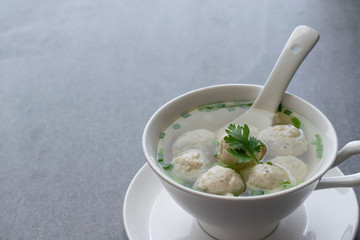 Chicken ball soup with scallion in white bowl on table.