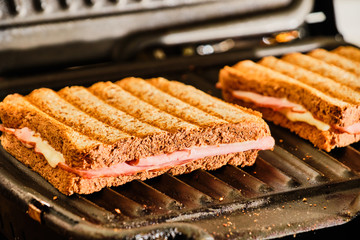 Preparing toast  with ham and cheese on grill