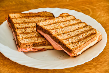 Toast  with ham and cheese on white plate
